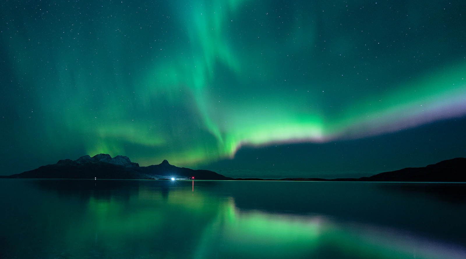Green aurora lights over a lake at night near Bodø