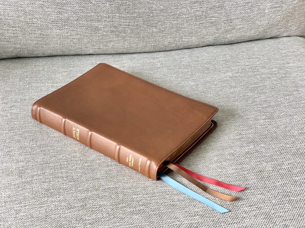 brown leather bifold wallet on gray textile