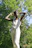 A happy customer wearing a stylish jumpsuit, smiling outdoors in natural light.