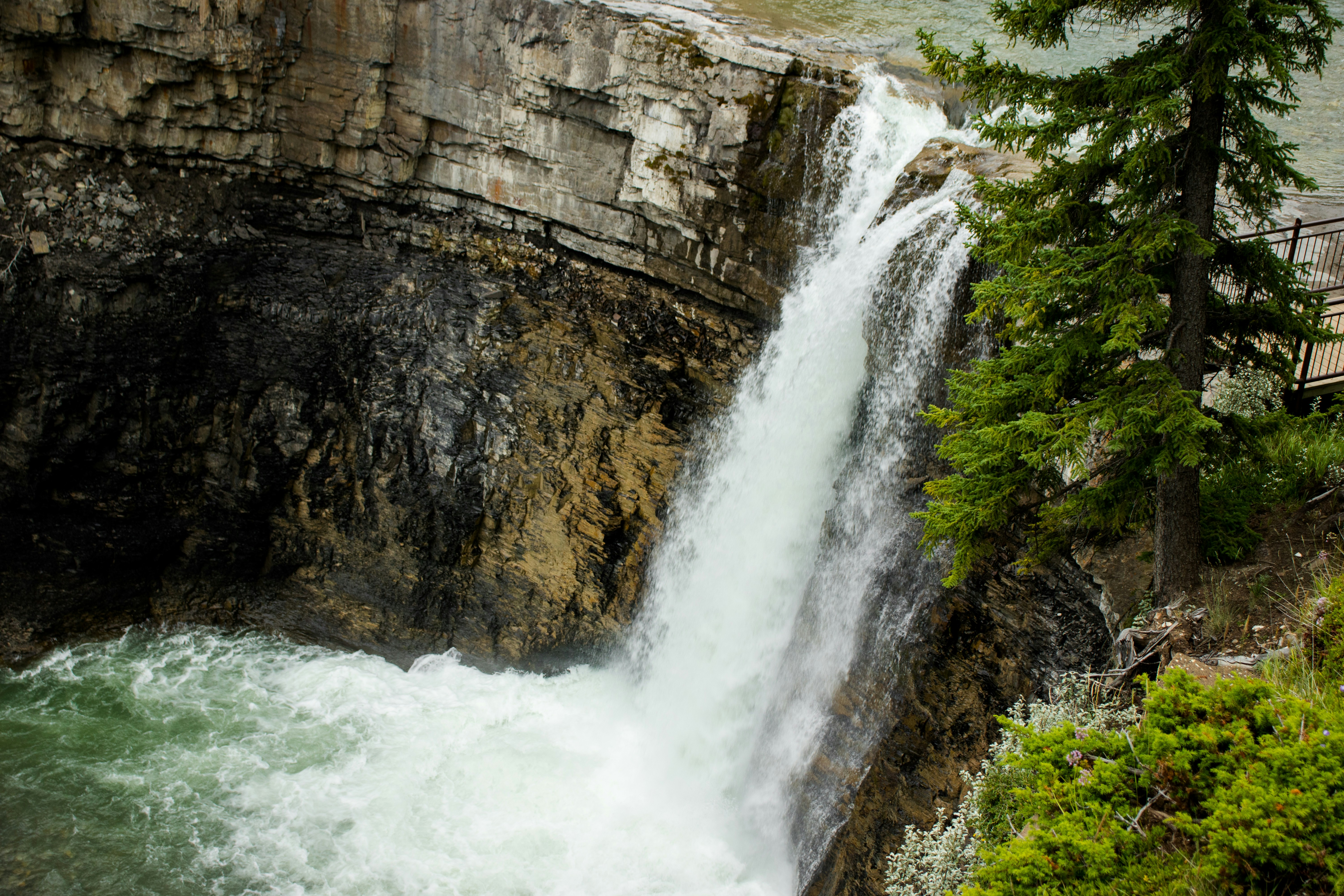 waterfalls between brown rocky mountain during daytime