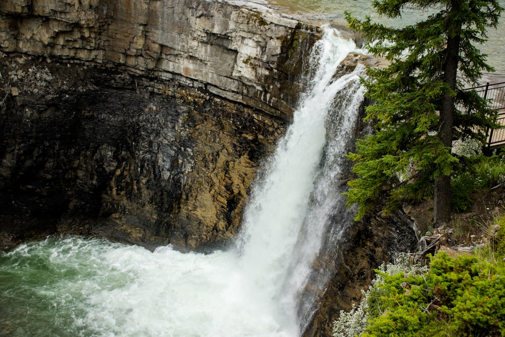 waterfalls between brown rocky mountain during daytime