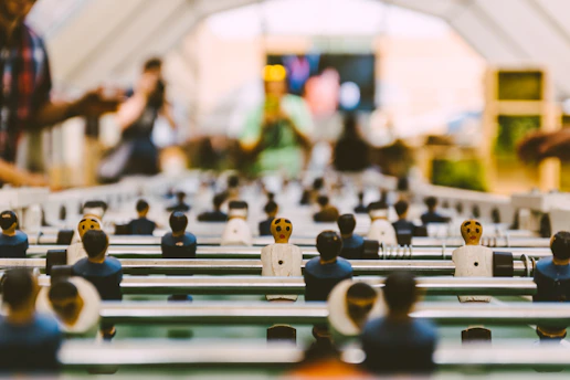 A lively foosball match in progress at žaidimo erdvė academy, with children focused and cheering.