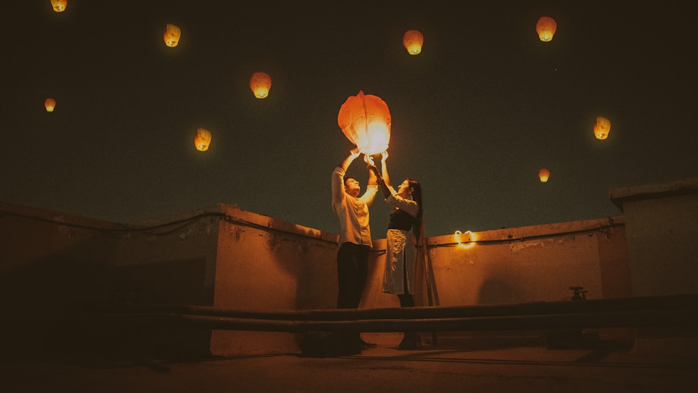 Uomo e donna in piedi sul tetto durante la notte