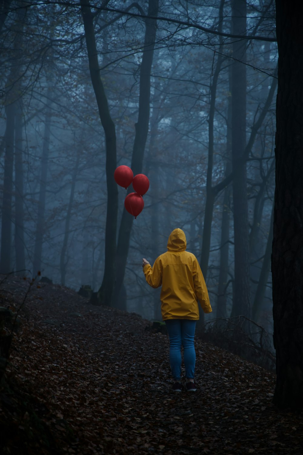 child in yellow hoodie standing on forest during daytime