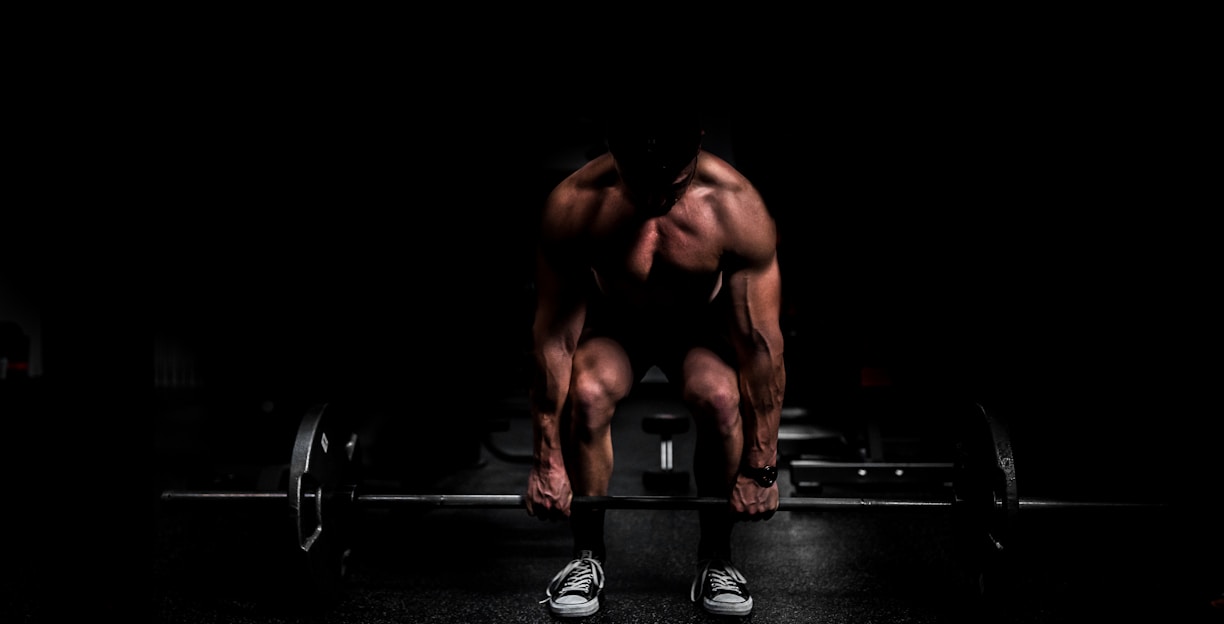 topless man in black shorts sitting on black and silver barbell