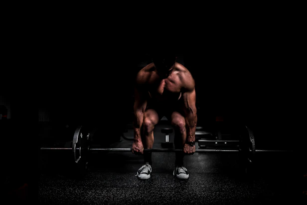 shirtless man lifting barbell in gym