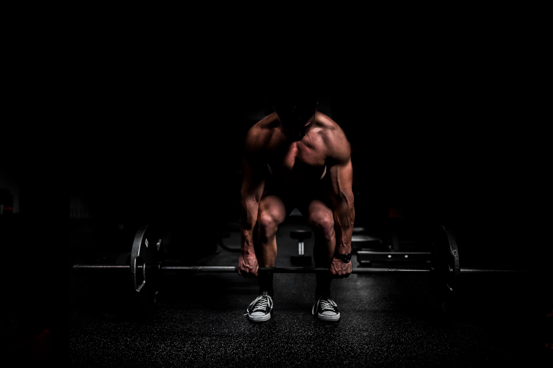 Krachtsporter maakt zich klaar voor een deadlift in een donkere ruimte