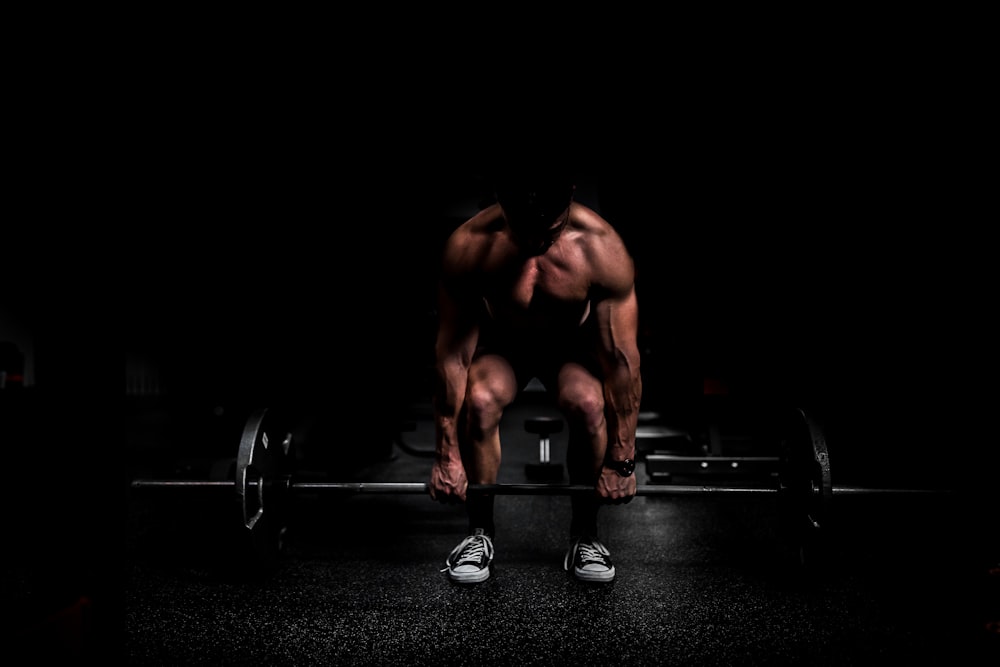 topless man in black shorts sitting on black and silver barbell