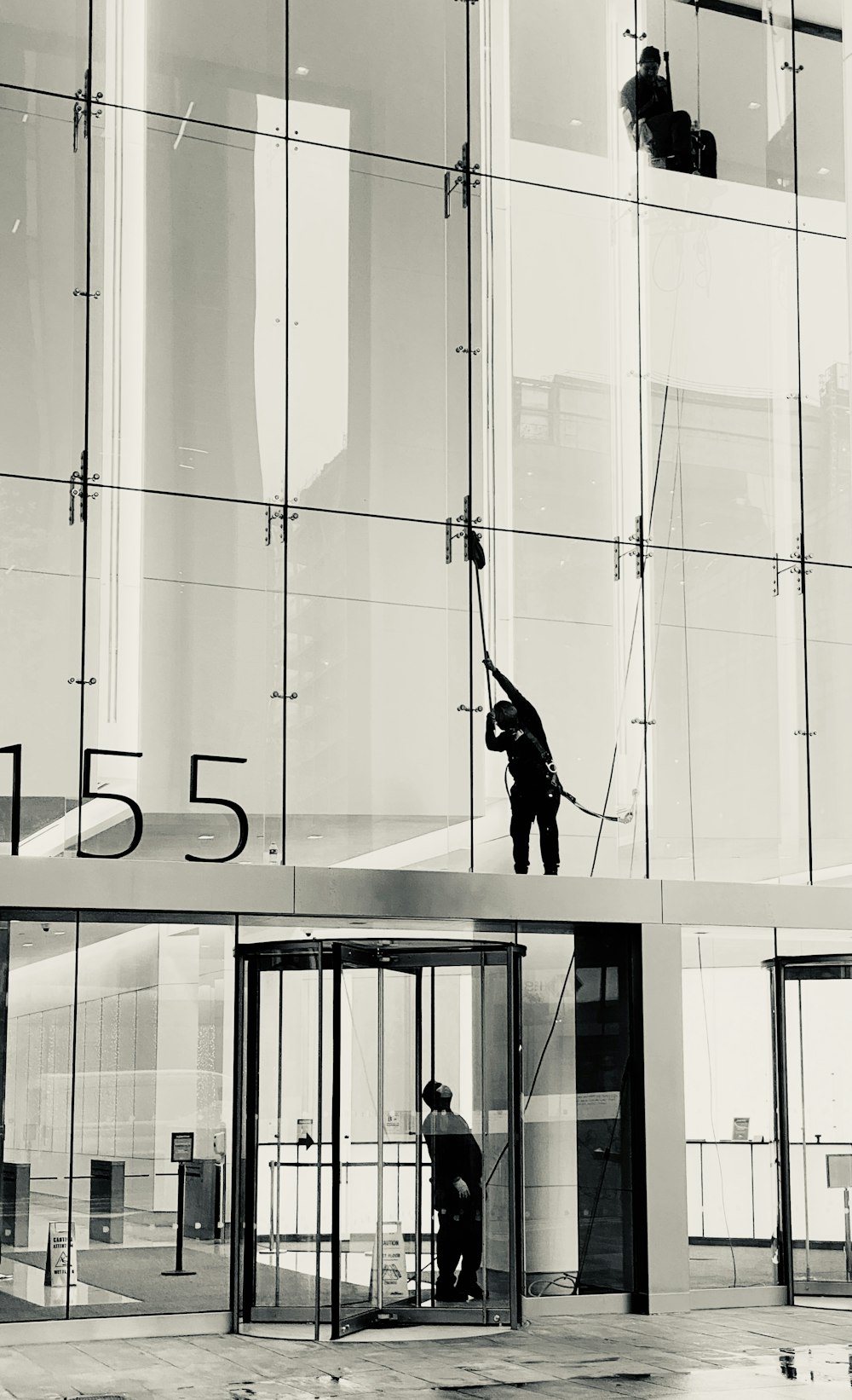 man in black jacket and pants standing on glass window