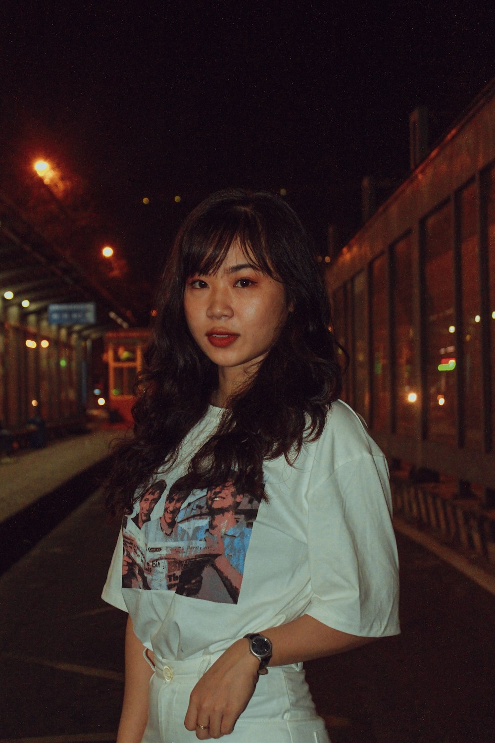 woman in white coat standing on sidewalk during night time