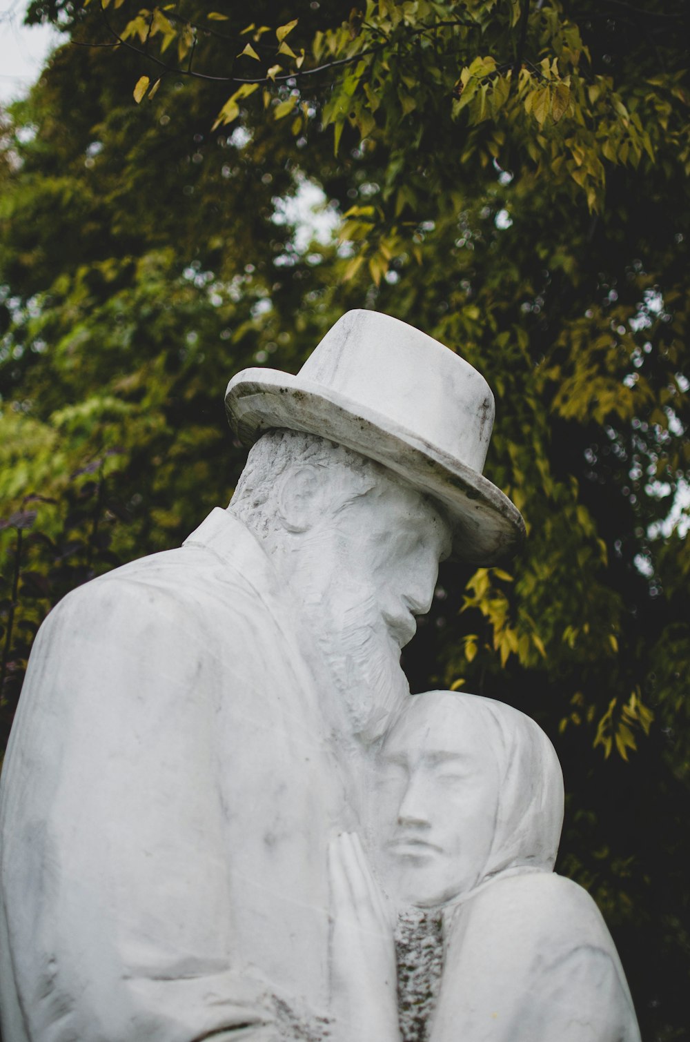 white concrete statue near green trees during daytime