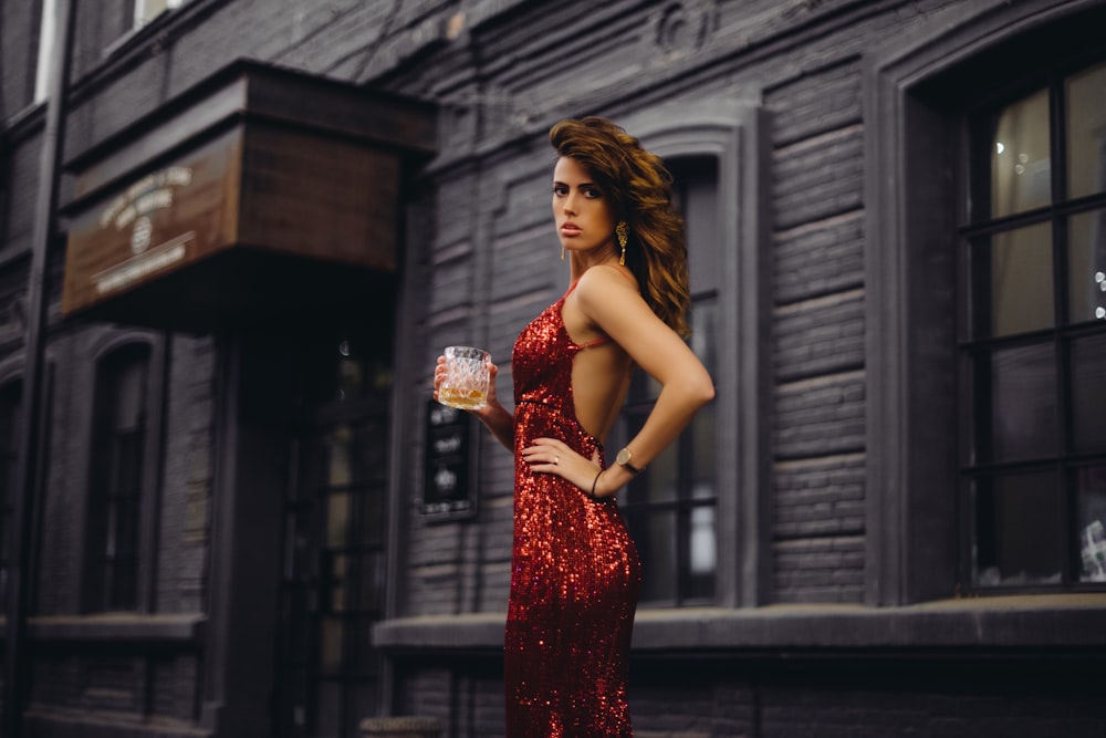 woman in red and gold floral sleeveless dress holding bouquet of flowers