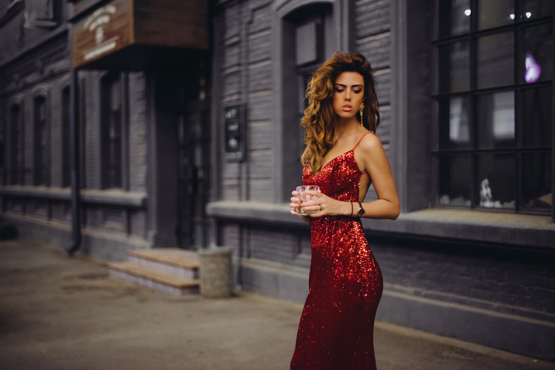 woman in red spaghetti strap dress standing on road during daytime
