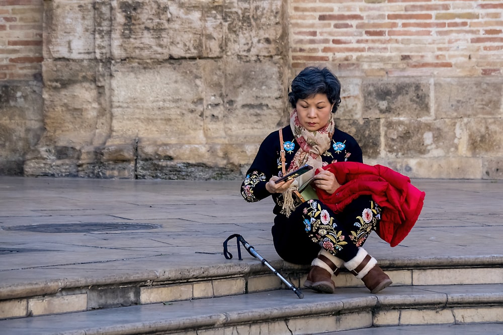 woman in red and black long sleeve dress sitting on gray concrete bench