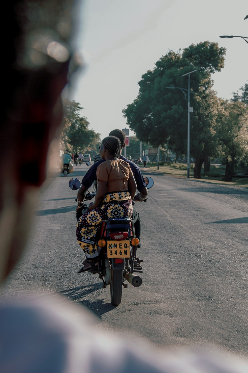 man in black and yellow floral shirt riding motorcycle on road during daytime