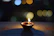 A serene image of a devotee lighting a diya lamp in a softly lit temple corner.