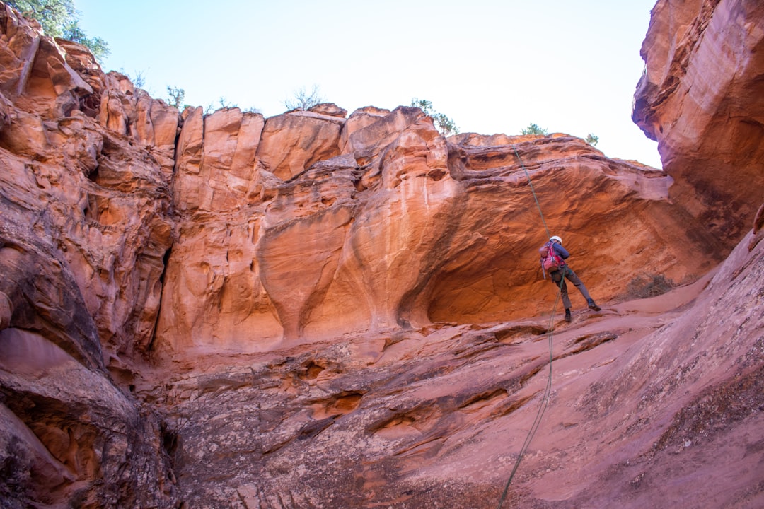 man in blue jacket and black pants climbing brown rock mountain during daytime