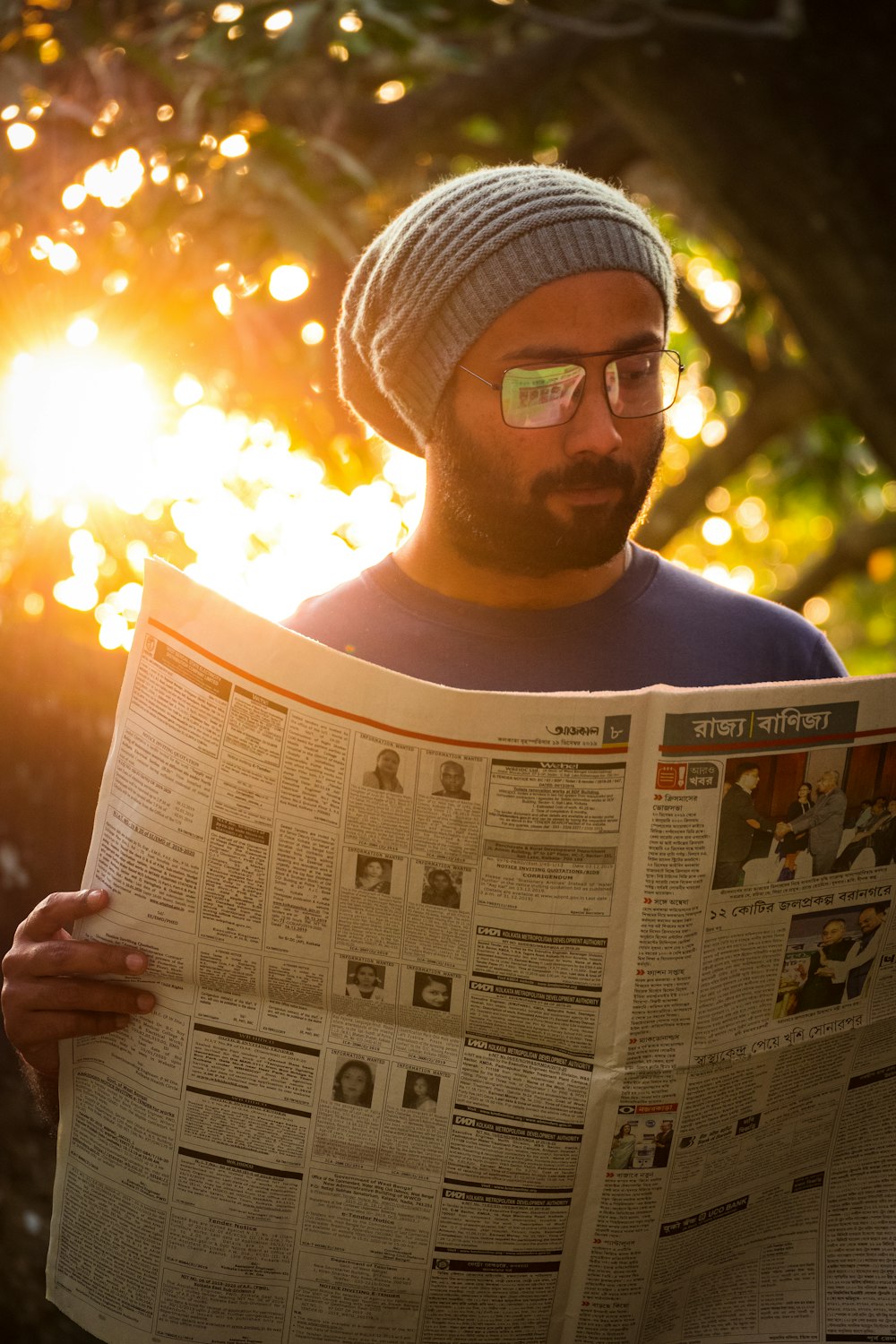 man in blue crew neck shirt holding newspaper