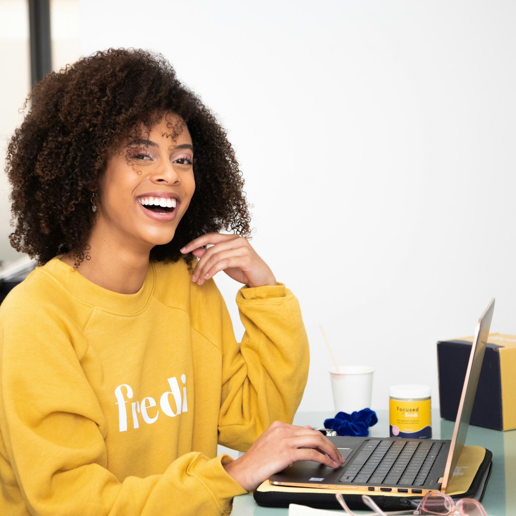 woman in yellow sweater sitting beside table with laptop computer