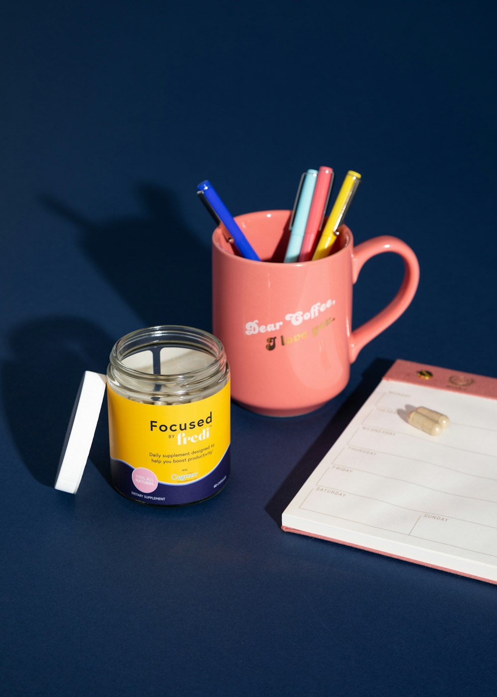 red ceramic mug with pens and pencils