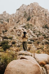 man in black jacket and brown pants standing on brown rock during daytime
