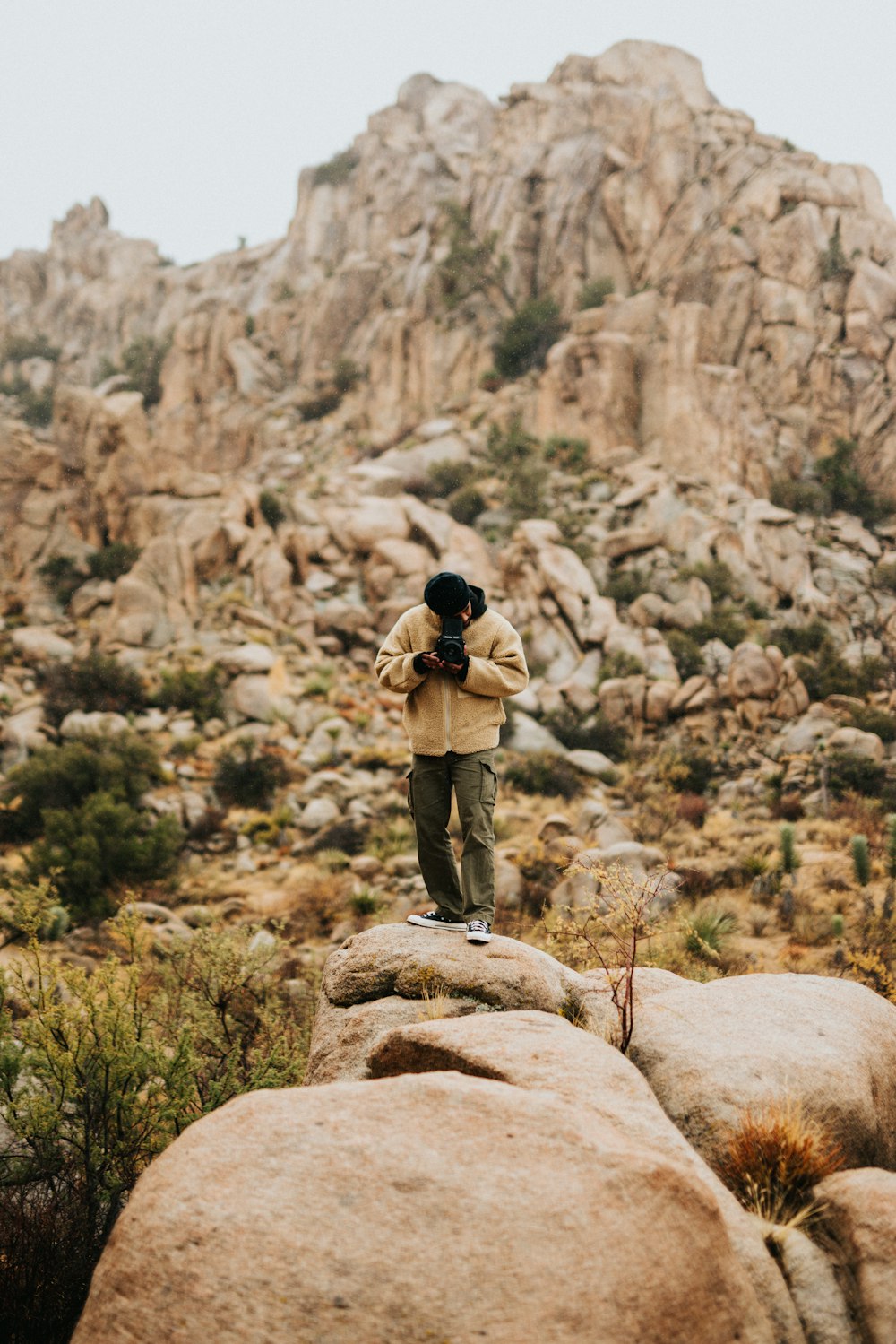 man in black jacket and brown pants standing on brown rock during daytime