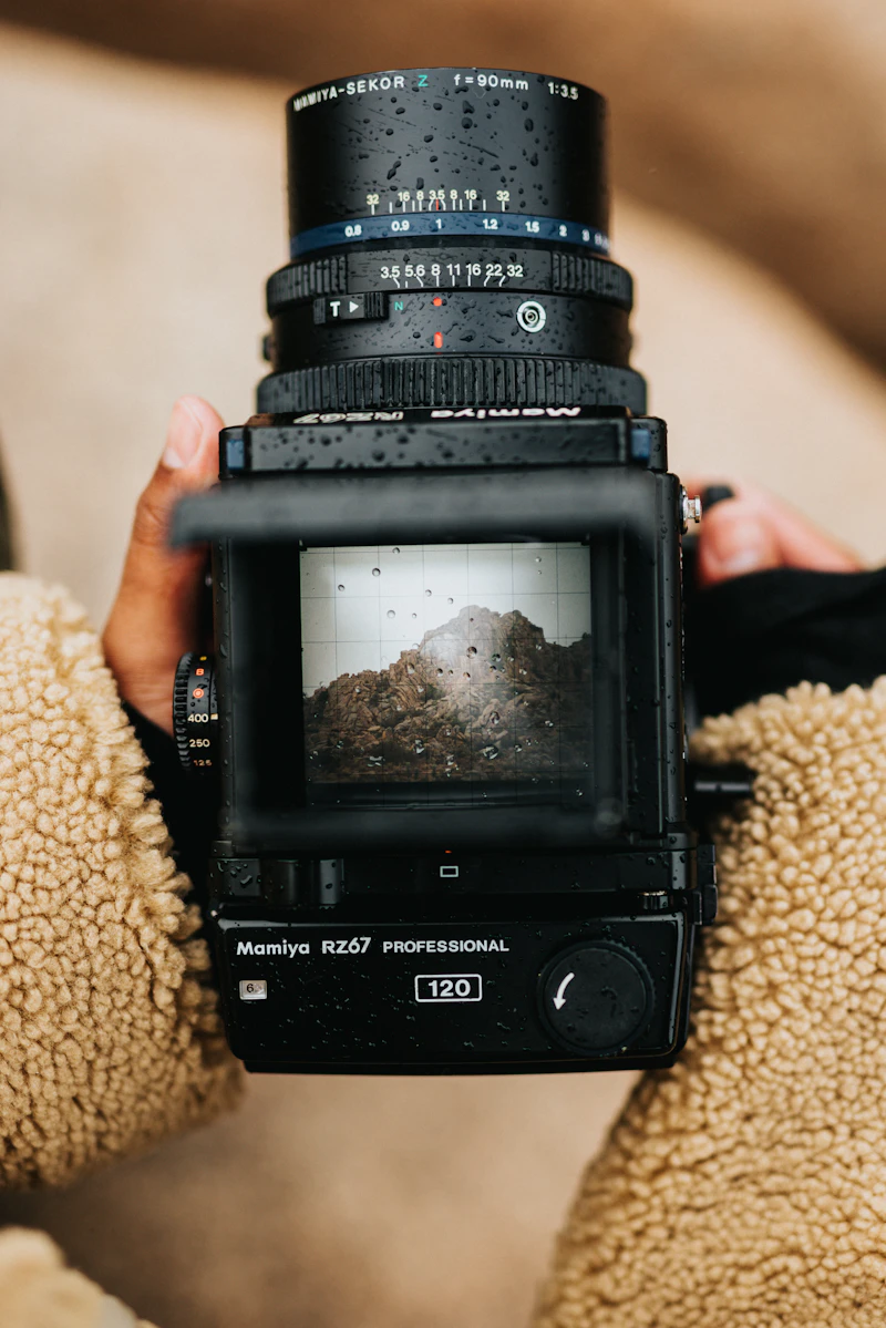 A photographer looking through the viewfinder of a medium-format film camera