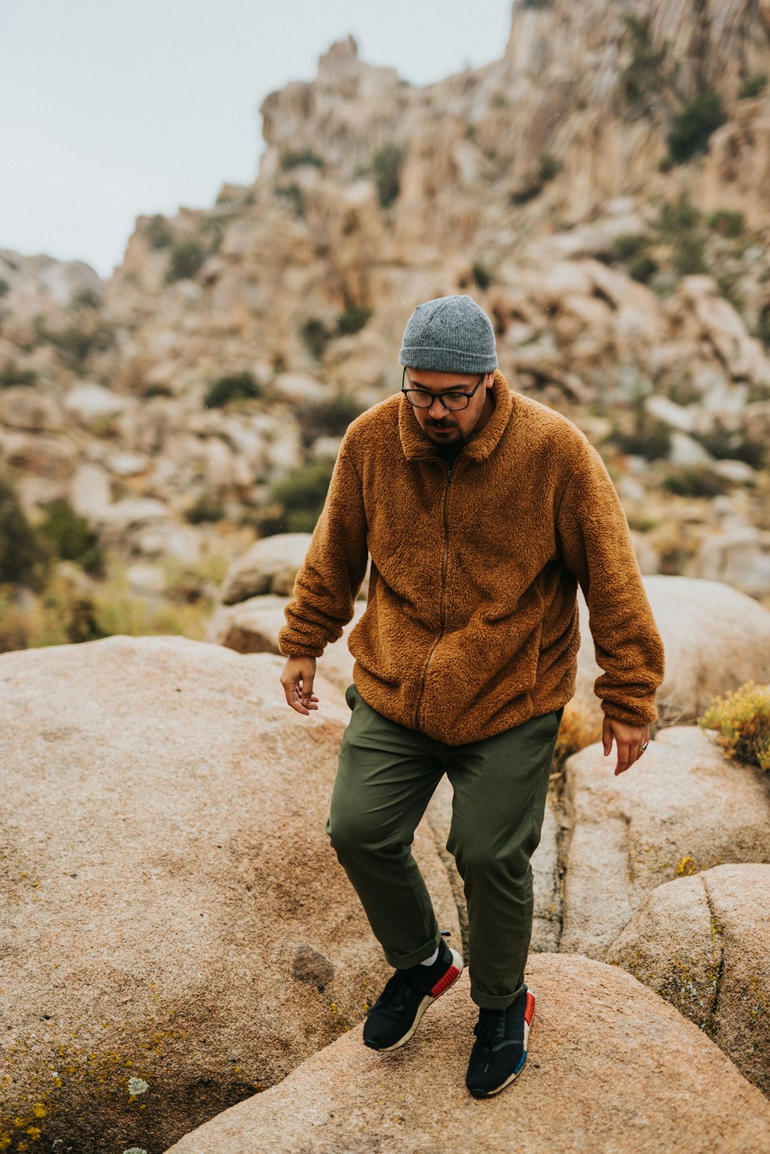 man in brown sweater and gray knit cap walking on brown sand during daytime