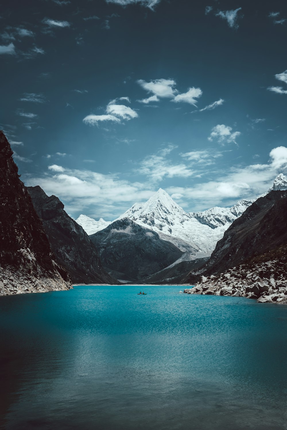 lake in the middle of mountains under blue sky