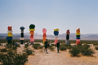 An artistic installation featuring bright colors and unique sculptures in a desert landscape.