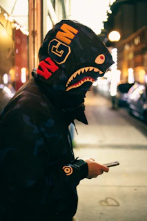 Model wearing a sleek streetwear jacket featuring Vaultara's signature logo in a nighttime cityscape