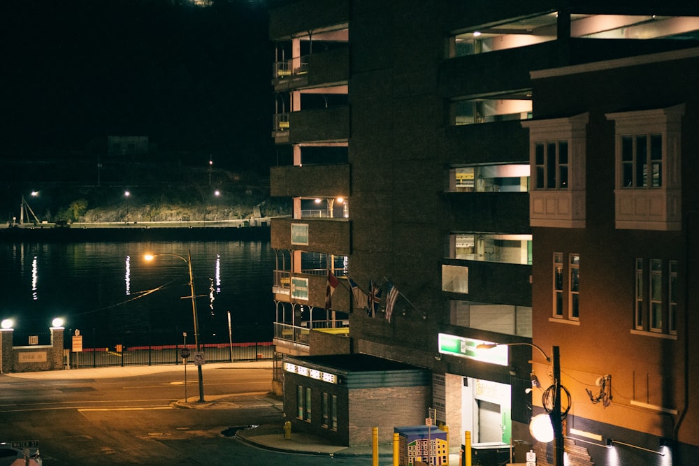 Bâtiment en béton brun près d’un plan d’eau pendant la nuit