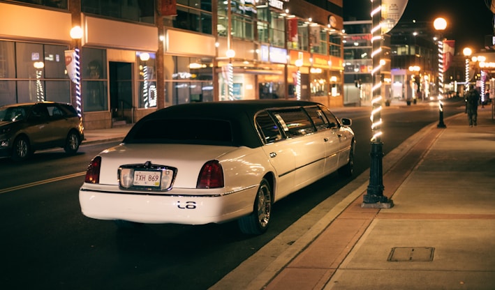 white sedan parked on sidewalk during night time