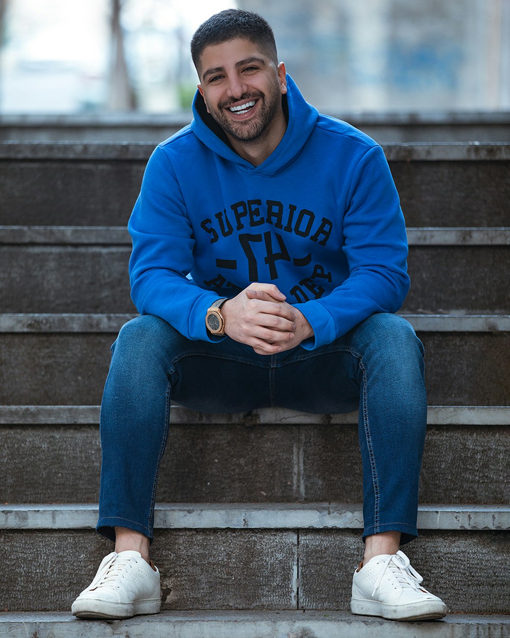 man in blue hoodie and blue denim jeans sitting on concrete stairs