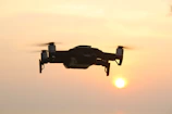 Industrial drone flying over a solar farm at sunset with detailed shadows.