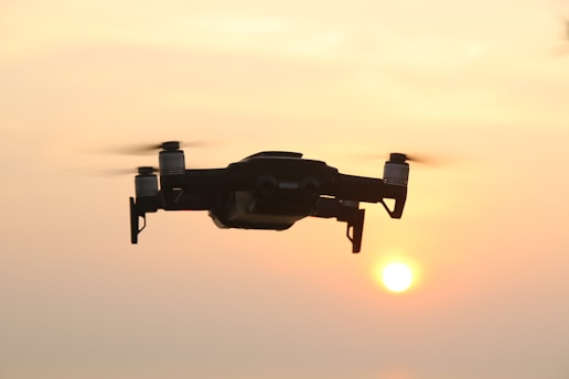 Drone flying over industrial plant capturing detailed aerial footage at sunset.