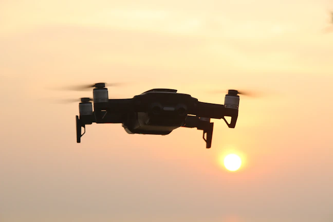 Industrial drone flying over a solar farm at sunset with detailed shadows.