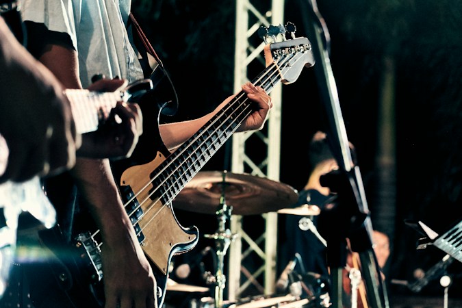 A guitarist playing on a lit stage, the kind of live local rock show on the Rio Concert Series lineup
