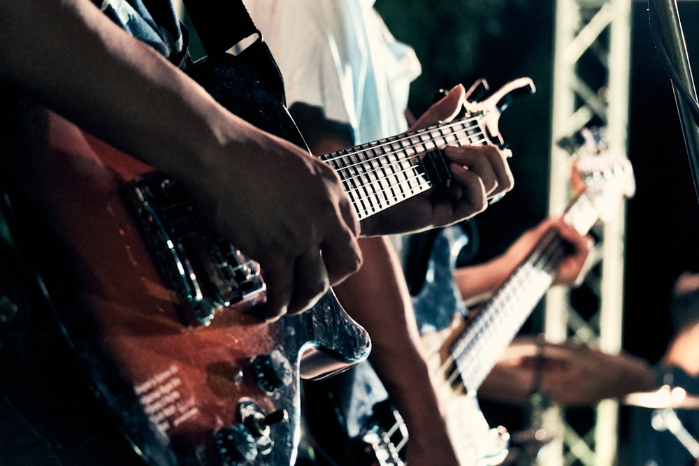 man in black vest playing brown electric guitar