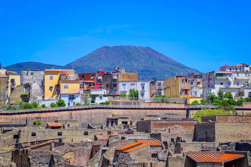 Edificios de hormigón marrón y blanco cerca de la montaña bajo el cielo azul durante el día