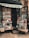 A small bookshop stall displaying a variety of books stacked in piles both inside and outside. The shop has an awning, and the books are arranged neatly across shelves and wooden pallets on the ground. Some book covers are partially visible, showing a mix of colors and book genres.