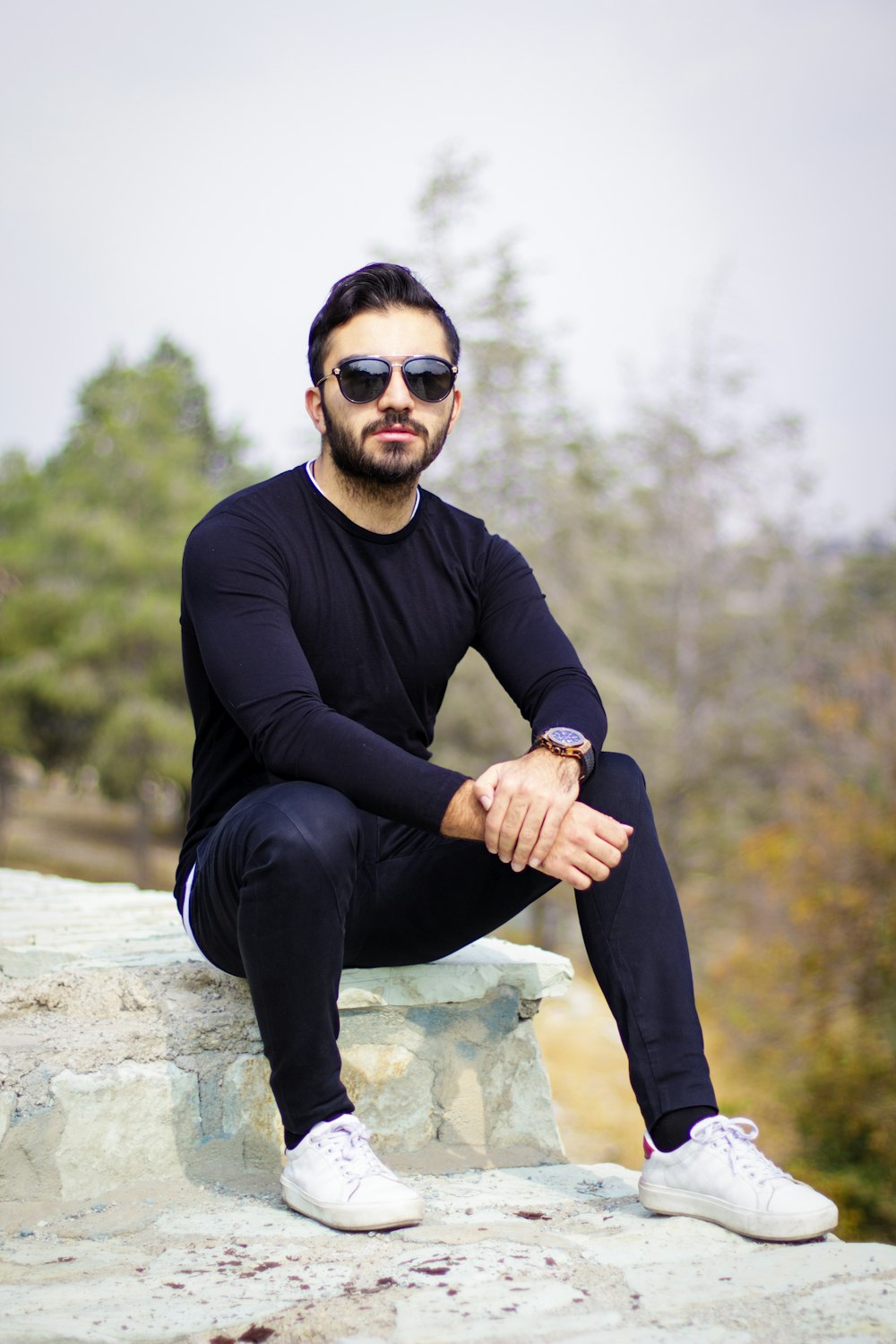 Foto Hombre con camisa negra de manga larga y pantalón negro sentado en una  roca – Imagen Zapato gratis en Unsplash