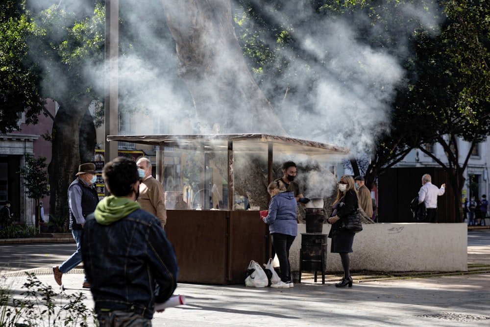 a group of people standing outside of a building with smoke coming out of it