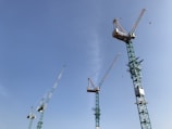 Several tall construction cranes extend into a clear blue sky, suggesting an area of significant construction and development.