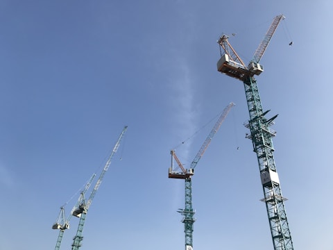 Several tall construction cranes extend into a clear blue sky, suggesting an area of significant construction and development.