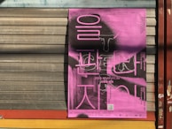 Staff member carefully folding a vibrant K-pop poster as part of the optional poster folding service.