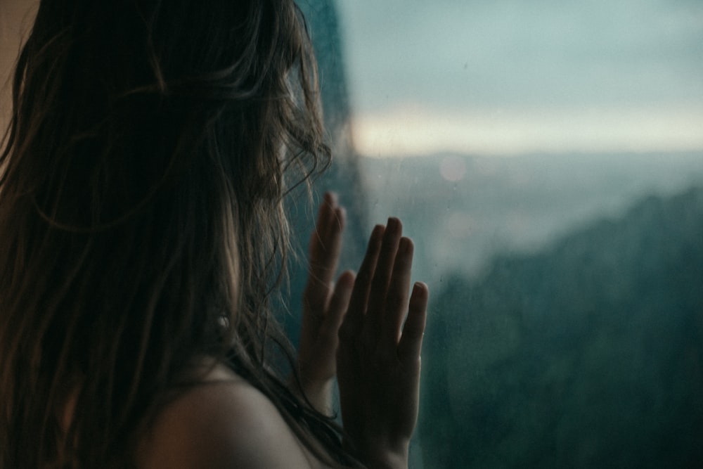 woman in black tank top covering her face with her hands