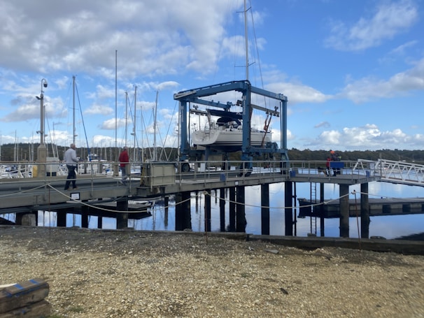 A fishing boat being gently lifted by a crane onto a transport vehicle.
