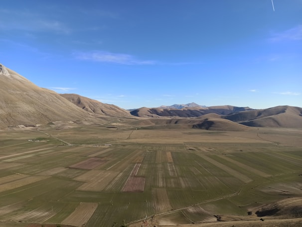 A flat terrain with a distant view of mountains and open fields.