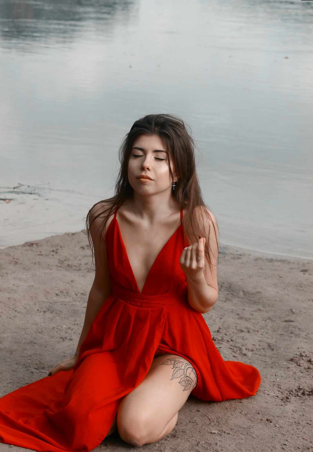 woman in red v neck dress sitting on brown sand during daytime